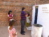 Ingang van het nieuwe toiletgebouwtje met het watervat voor de hand bediende spoeling